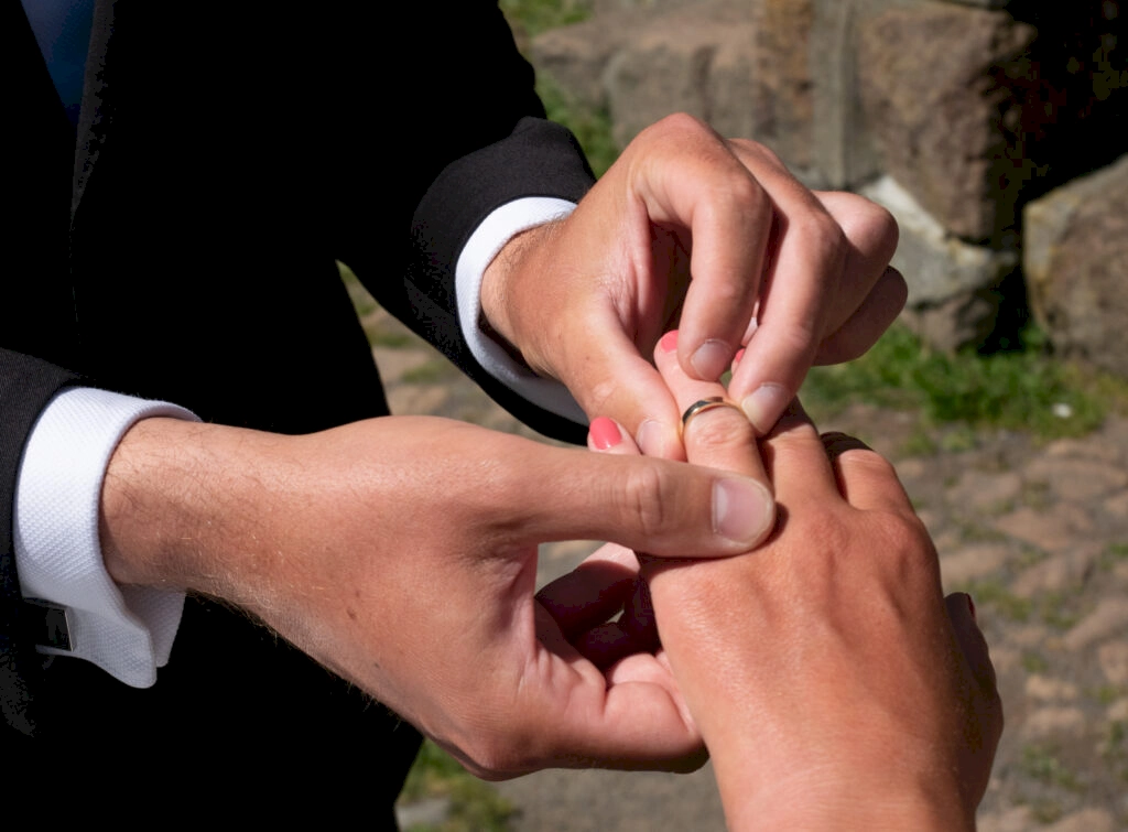 Stewart, the groom, places a wedding ring on the bride, Zoe's finger. Picture taken at Sign of the Bell Bird, Port Hill, New Zealand during a wedding elopement.