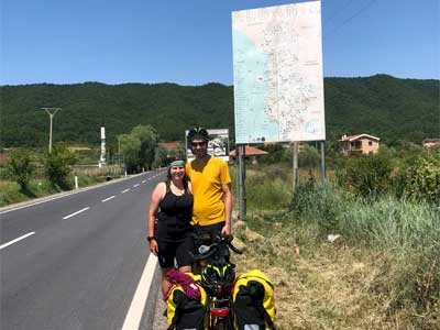 Zoe and Stew stood at the sign to Albania with our steel frame touring bikes
