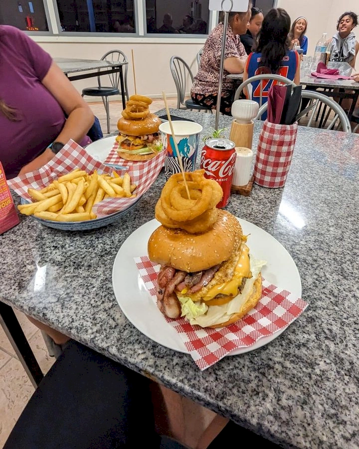 Two very large burgers stacked with onion rings and fries served at Mundrabilla roadhouse along nullarbor plain. A perfect meal for two hungry cyclists.
