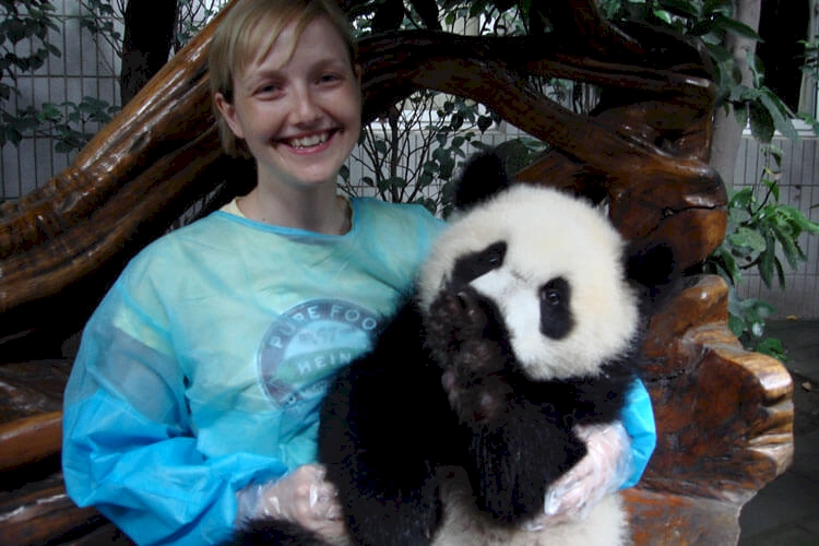 Garry and his wife with a baby panda at the chengdu panda sanctuary. A blonde woman is holding the panda in her arms.