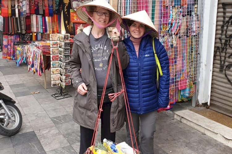 zoe and julie dressed with hats and a fruit basket by two hanoi women